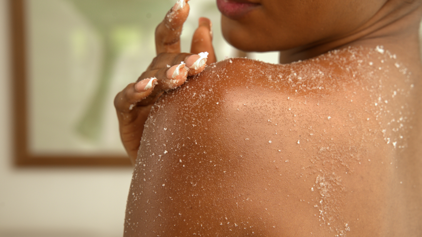 Person applying salt scrub on their shoulder