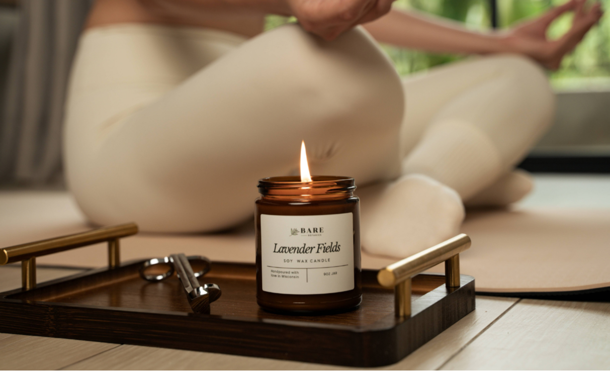 Candle labeled 'Lavender Fields' from Bare Botanics on a tray with a person meditating in the background